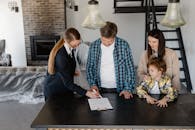Happy family signing a real estate contract with agent inside their new home.